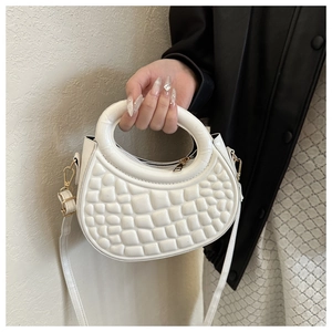 Detail view of the white half-moon bag featuring geometric embossed texture and gold zipper