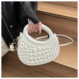 Close-up of a white handbag with 3D embossed square pattern and gold hardware
