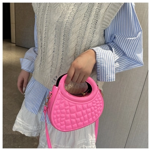 Detail of bright pink semi-circular quilted handbag with leather strap and top handle