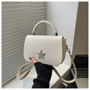 Detailaufnahme der cremefarbenen Web-Tasche mit glitzerndem Strassstern und Kette