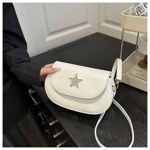 Detail view of the silver star-shaped hardware with sparkling stones on the white saddle bag