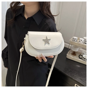 Detail of white half-moon saddle bag featuring a sparkling silver rhinestone star buckle