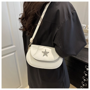 Detail of white star buckle saddle bag with adjustable strap worn on model's shoulder