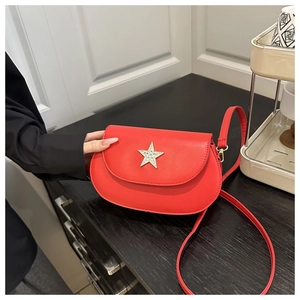 Detail of red saddle bag with rhinestone star buckle on dark wood background