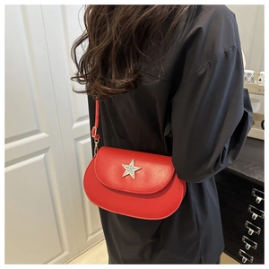 Side view of a bright red semi-circular crossbody bag with a silver star on model