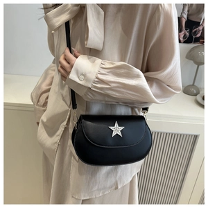 Detail of a black leather saddle bag featuring a silver rhinestone star buckle and strap
