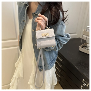Close-up of mini white handbag with faux crocodile texture and gold lock clasp