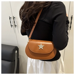 Detail view of brown saddle bag featuring a large silver sequin star and adjustable strap