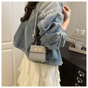 Detailed close-up of light gray crocodile textured mini handbag with golden metal lock