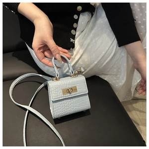 Detail of light blue crocodile embossed mini handbag with gold metal lock and handle