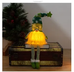 Close-up of a glowing Christmas gnome with long legs and a knitted snowflake hat on a trunk
