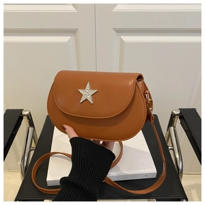 Detail of brown saddle bag with silver sparkling star buckle and matte finish texture