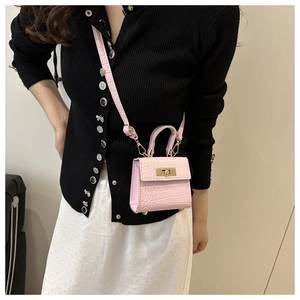 Detailed view of a pink mini crossbody bag with crocodile texture and gold hardware