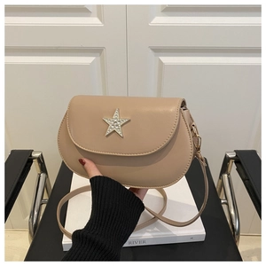 Detail view of beige saddle bag with sparkling rhinestone star buckle and fine strap