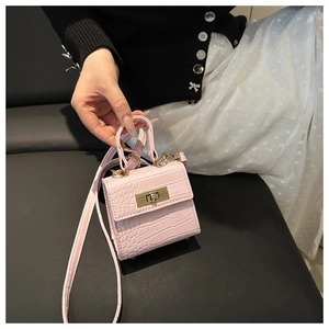 Close-up of pink crocodile texture mini handbag with golden metal lock and single handle