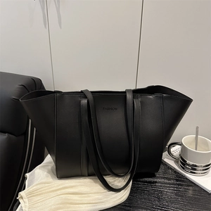 Minimalist black leather tote bag with FASHION logo on a dark wooden table background