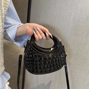 Glossy black embossed leather handbag with top handle and gold detachable crossbody strap