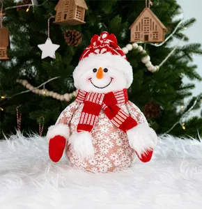 Close-up of a festive plush snowman with red knit hat and scarf on a white fluffy rug