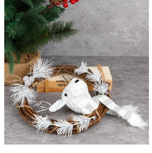 Detail of Christmas wreath with white plush reindeer, gray scarf, and pine needles decor
