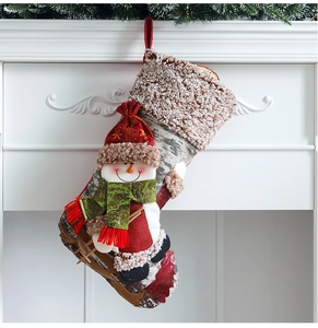 Detail of burlap Christmas stocking with plush snowman applique hanging on a fireplace