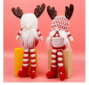 Detail van twee kerstkabouter knuffels met rendiergewei tegen een zachte oranje achtergrond