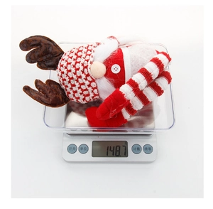 Gedetailleerd bovenaanzicht van een kerstgnome knuffel van 148,7 gram op een digitale weegschaal