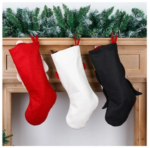 Trois chaussettes de Noël rouges blanches et noires suspendues à une cheminée en bois
