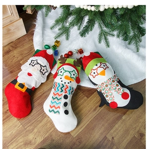Détail de trois chaussettes de Noël en feutre avec motifs Père Noël, Bonhomme et Pingouin