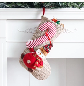 Detail of knitted Christmas stocking with 3D snowman and candy cane by fireplace
