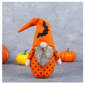 Gnomo di Halloween con cappello arancione a pipistrello e barba vicino alla zucca