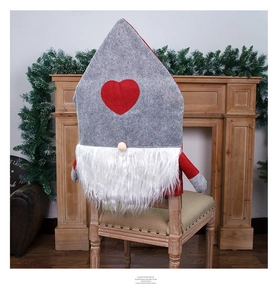 Detail of Nordic gnome Christmas chair cover with grey felt hat and red heart on wooden chair