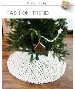Detail of white plush Christmas tree skirt with golden stars on wooden floor
