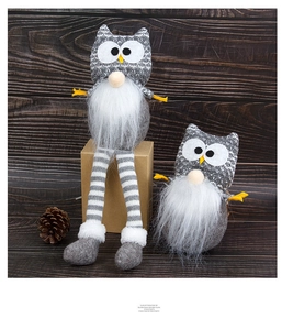 Detail of forest style owl plush dolls with long striped legs on wooden surface