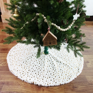 White plush Christmas tree skirt with gold star sequins on a warm wooden floor