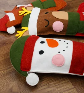 Close-up of felt Christmas stockings with cartoon deer and snowman on wooden floor