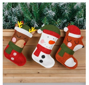 Close-up of three felt Christmas stockings featuring elk, snowman, and fox on wooden shelf