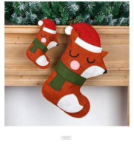 Detail of fox-shaped felt Christmas stockings in two sizes hanging on a wooden mantel
