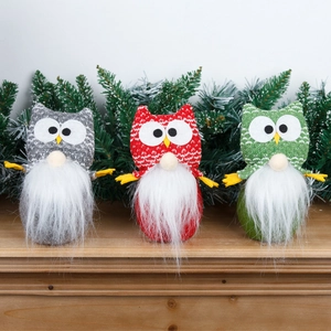 Three Christmas gnome owl dolls in grey, red, and green on a wooden table with snowy branches