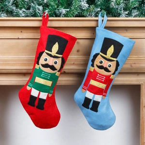 Set di calze di Natale rosse e blu con schiaccianoci ricamati appese a un caminetto