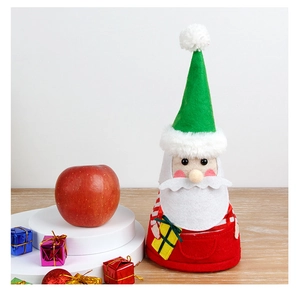 Detail of Santa felt doll with green hat and red striped sleeves on wooden surface