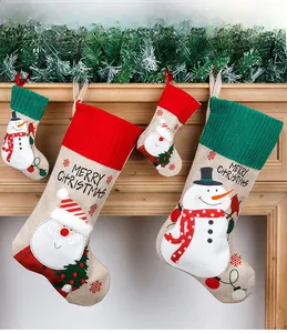 Detail of embroidered burlap Christmas stockings with Santa and Snowman hanging on a mantel