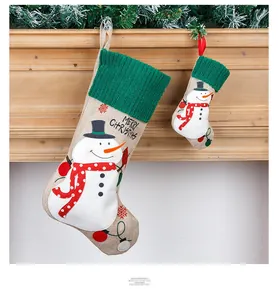 Detail of burlap Christmas stockings with snowman embroidery hanging on a fireplace