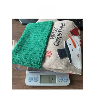 Linen Christmas stocking with snowman embroidery being weighed on a scale showing 72.7g