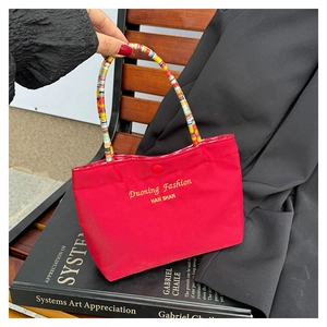 Detail der roten Canvas-Tasche mit gelber Stickerei und bunt geflochtenen Seilgriffen