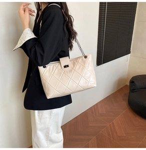 Detailed close-up of beige quilted tote bag with silver chain strap and turn-lock closure
