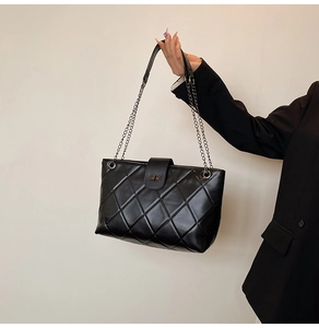 Detail of black quilted tote bag with silver chain strap and metal turn-lock closure