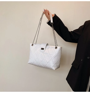 Detail of white quilted tote bag with metallic chain strap and twist lock closure