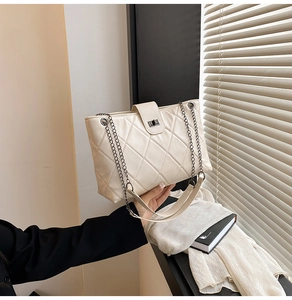 Detailed view of beige quilted tote bag with chain strap and metallic twist-lock closure
