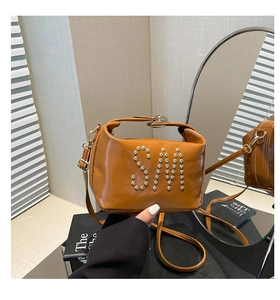 Gros plan du sac cabas marron avec clous argentés en motif SM et poignée réglable