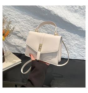 Detail der cremeweißen Kunstledertasche mit hellgoldem Metalldrehverschluss für Damen